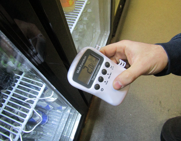 Engineer checking fridge temperature with a digital thermometer
